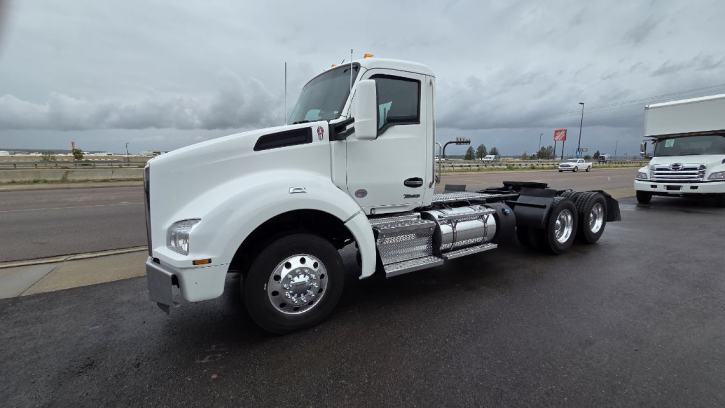 Semi truck tractor cab side view showing front hood, chrome fuel tanks, and dual rear axles. No text legible on image beyond general vehicle features.