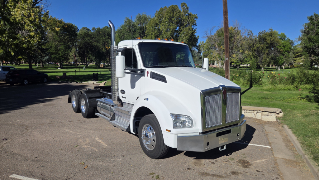 Kenworth T880 conventional daycab truck in white, front-left view, showing dual rear axles, chrome grille, and side mirrors.