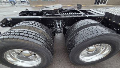 Kenworth T880 chassis view showing dual rear axles and fresh tires, rear frame with components.