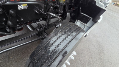 Front left wheel and suspension area of a 2022 Kenworth T880 with visible tire tread and chassis components