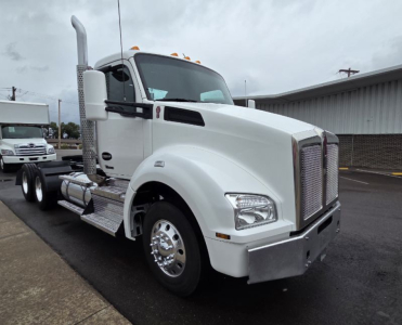 Kenworth T880 single-axle daycab truck in white, front three-quarter view. Visible text includes Kenworth logo on grille, fuel tank and steps, and side exhaust stack.