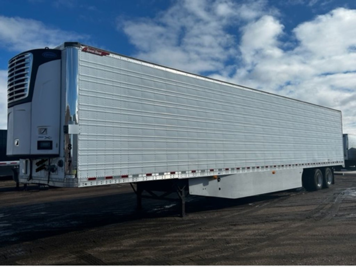 Great Dane reefer trailer with side panels, refrigeration unit, and dual rear axles; silver exterior; low front landing gear visible.