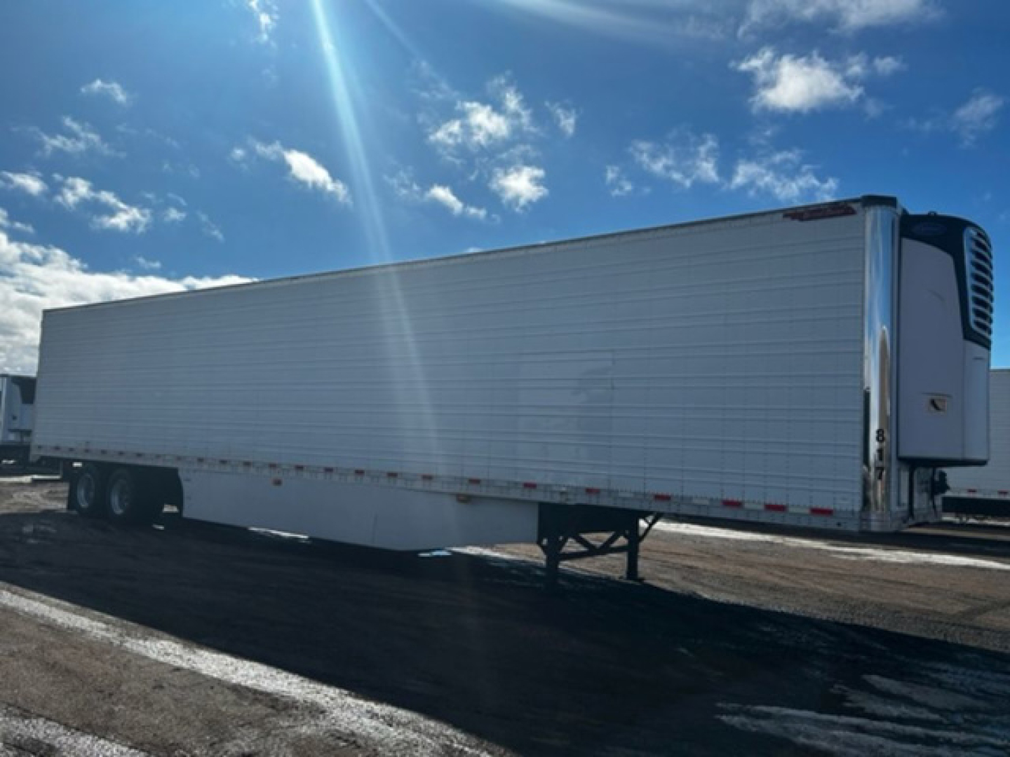 Great Dane reefer trailer side view showing refrigerated unit at front, tandem axles, and standing legs in a parking lot.