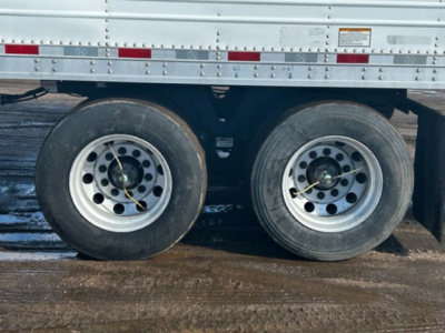 Great Dane reefer trailer side view showing dual axles and wheels with inner hubs and tires; top of wheel area shows reflective tape and side panel with rivets.