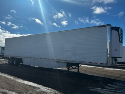 Great Dane reefer trailer side view showing refrigerated unit at front, tandem axles, and standing legs in a parking lot.