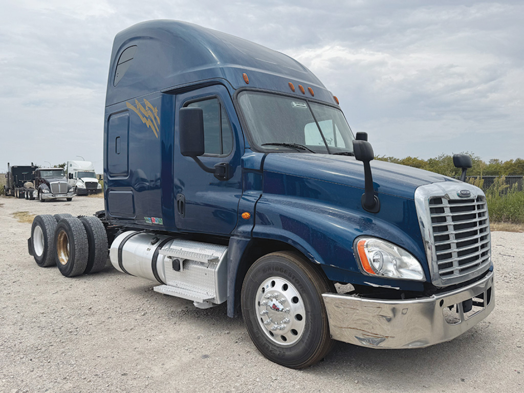 Truck cab of a 2020 Freightliner Cascadia125 Conventional Sleeper, blue exterior, three axles, front chrome bumper, large grille, side fuel tanks, stock number 557107 and VIN LDLG3254 visible.