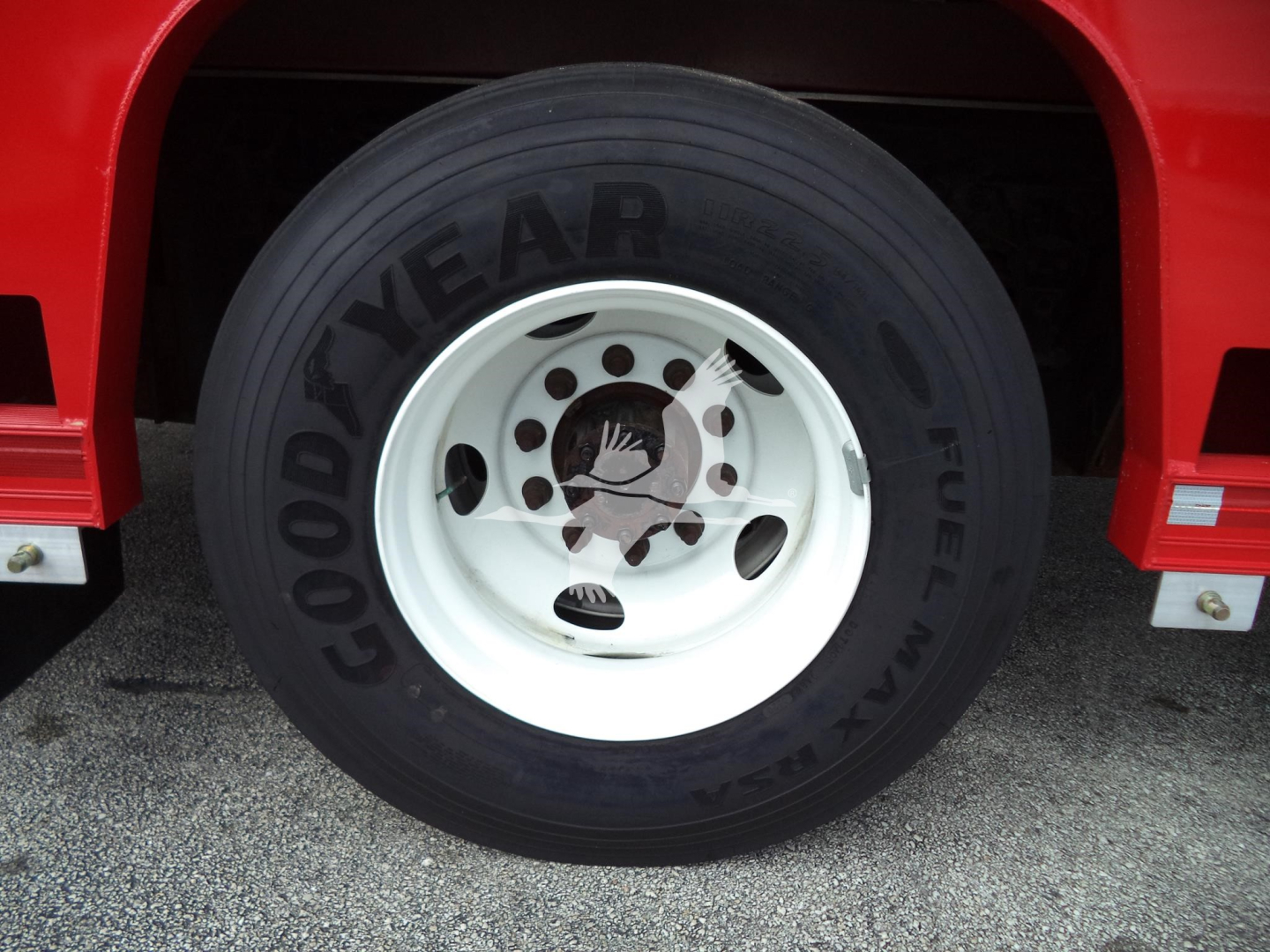 Goodyear tire on a red Ford F650 front wheel with white steel rim and hub cover, undercarriage visible.