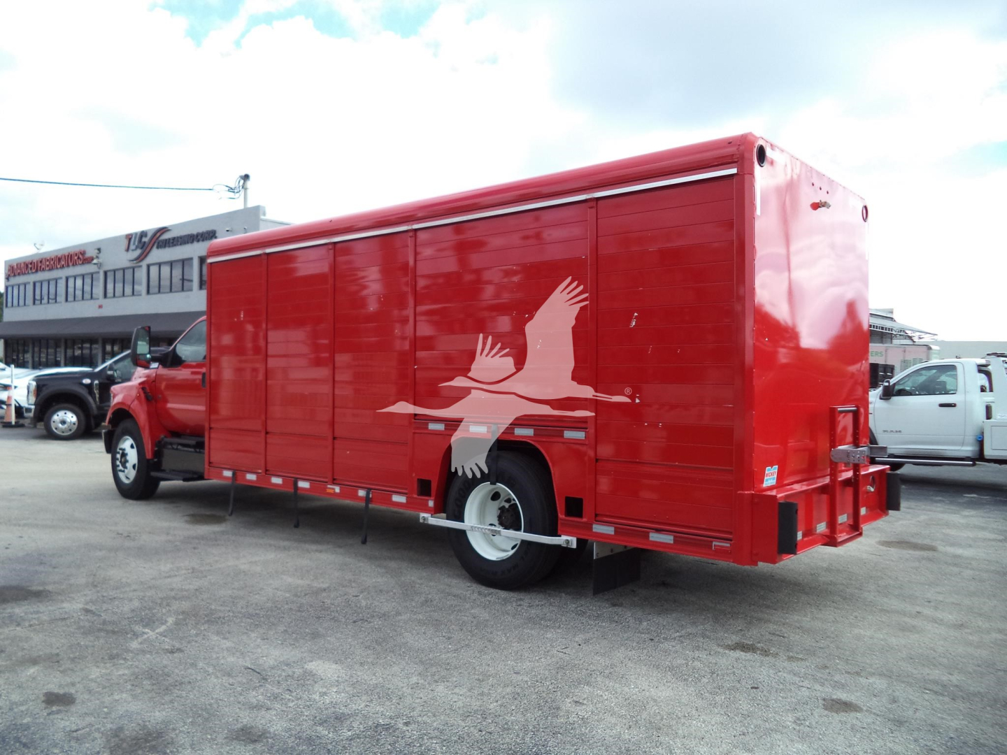 Red Ford F650 service truck with enclosed box, showing side silhouette graphic and rear taillight area.