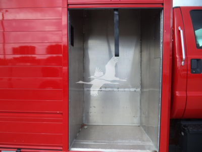 Utility truck cargo area with open rear, red exterior, empty metallic cargo box, white graphic of two birds in flight on inner wall.