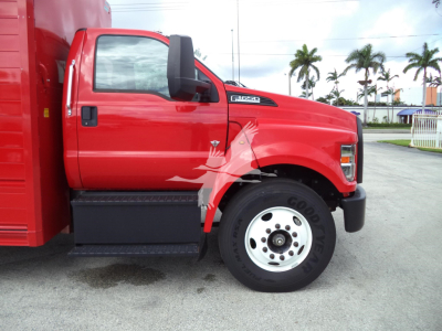 Ford F-650 service truck side view showing front wheel and red cab with F-Series badge and black front bumper.