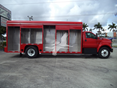 Service/utility truck body on a red Ford F650 with open compartments along the side, white eagle graphic overlay.