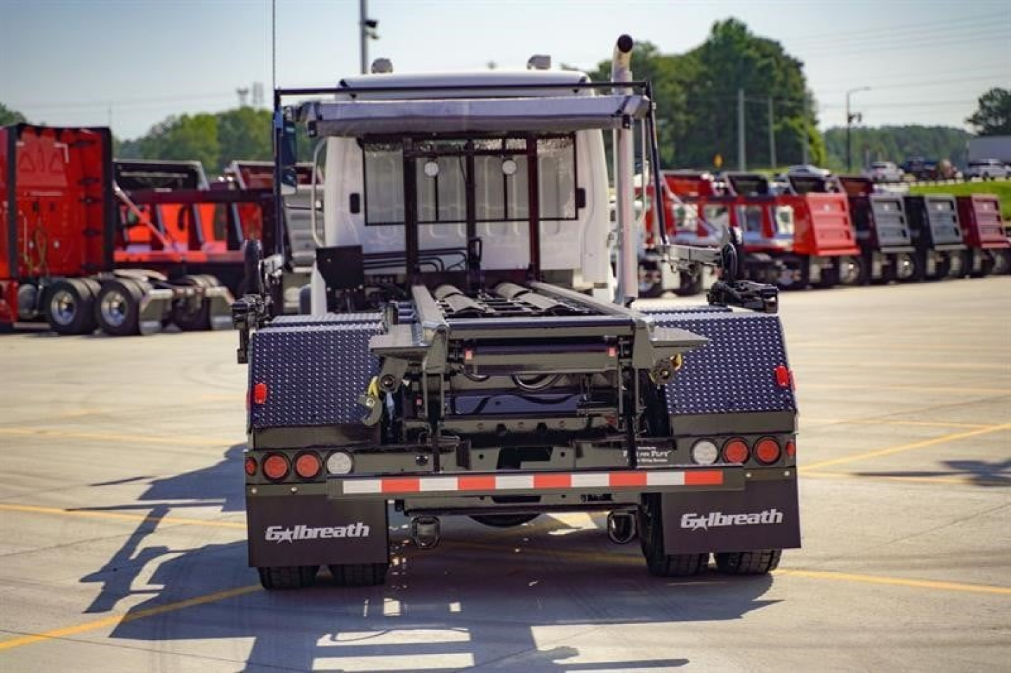 Freightliner 114SD roll-off truck rear view showing hydraulic hitch and metal steps with brand name Galbreath on mud flaps.
