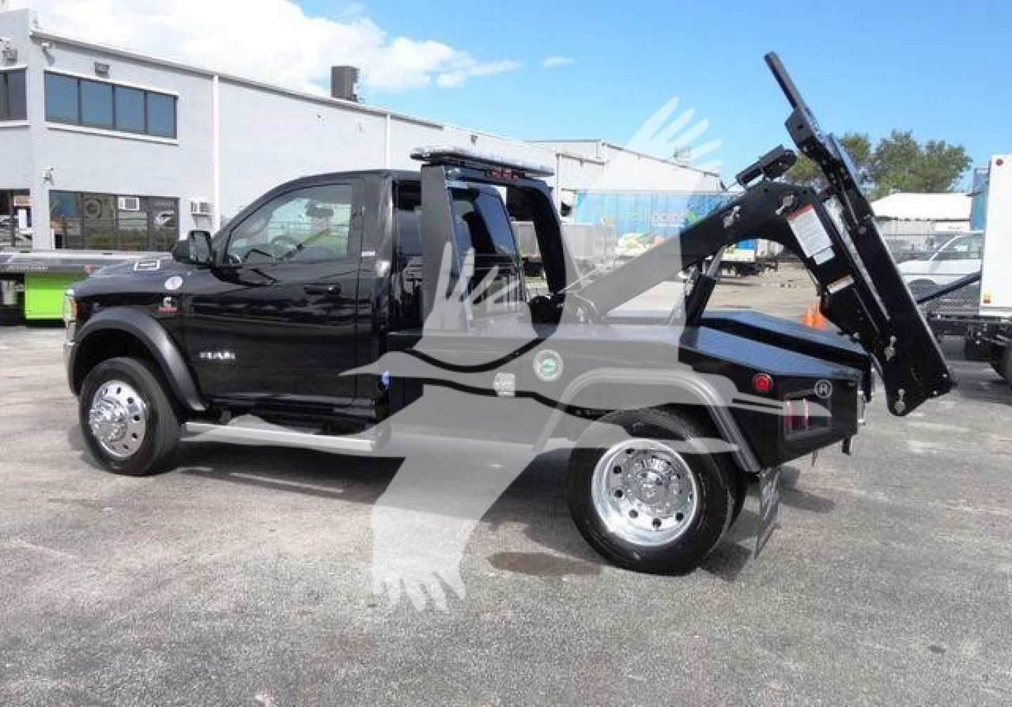 Ram 4500 SLT pickup with a bed-mounted hydraulic tow winch system, black exterior, dual rear wheels, side running boards, and chrome wheels in a dealership lot.