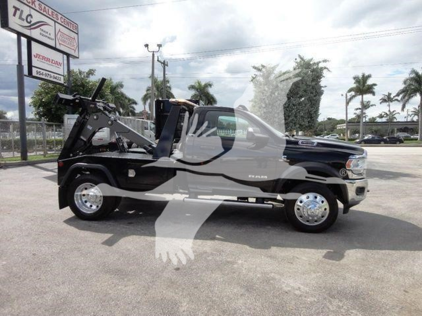 2024 Ram 4500 SLT tow truck side view with winch equipment in bed, black exterior, chrome wheels, dealership lot visible in background.