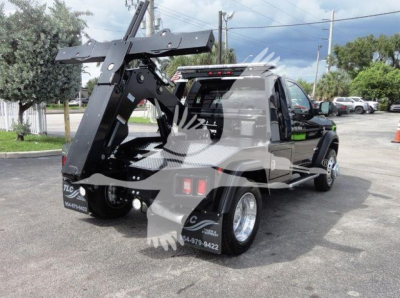 Ram 4500 SLT pickup with a heavy-duty hydraulic tow boom and winch system mounted at rear, black exterior, chrome wheels, dual rear wheels, license-like decals on tail.