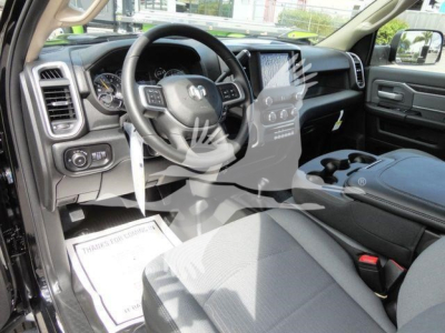 Ram pickup interior showing steering wheel, dashboard, center console, and front seats; light gray upholstery and modern infotainment screen visible.
