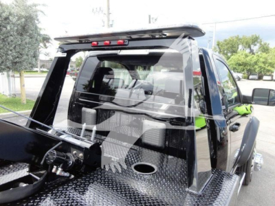 Truck bed of a new 2024 Ram 4500 SLT with winch setup and diamond plate bed, rear cab window, and towing hardware visible.