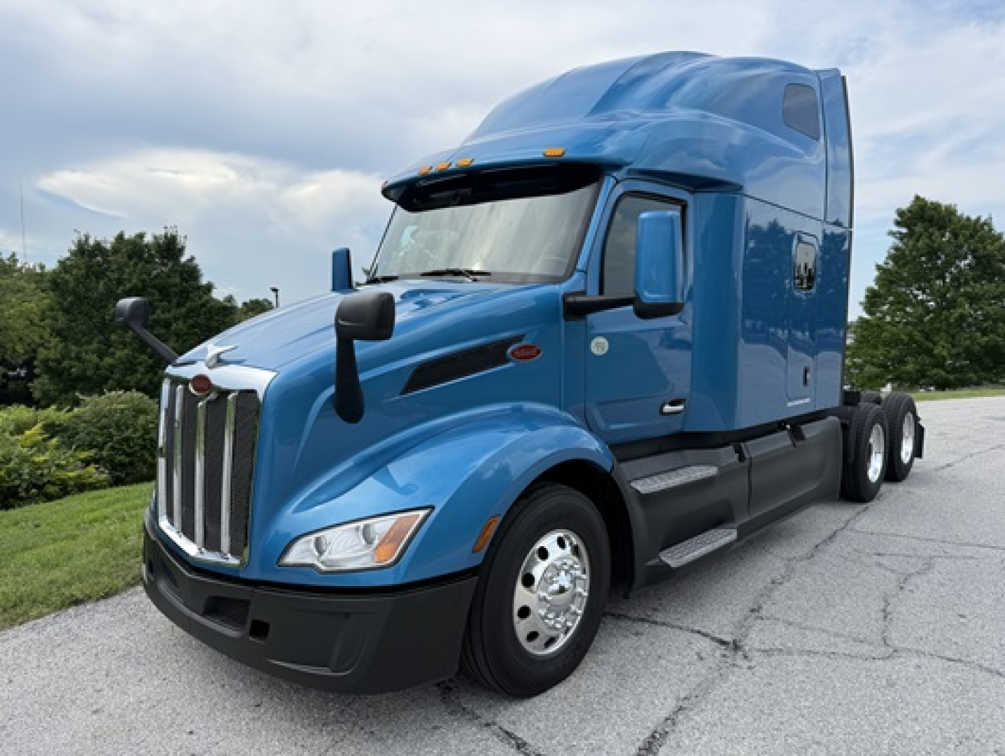Peterbilt 579 semi-truck in blue, sleeper cab, front and side view with chrome grille and dual rear axles.