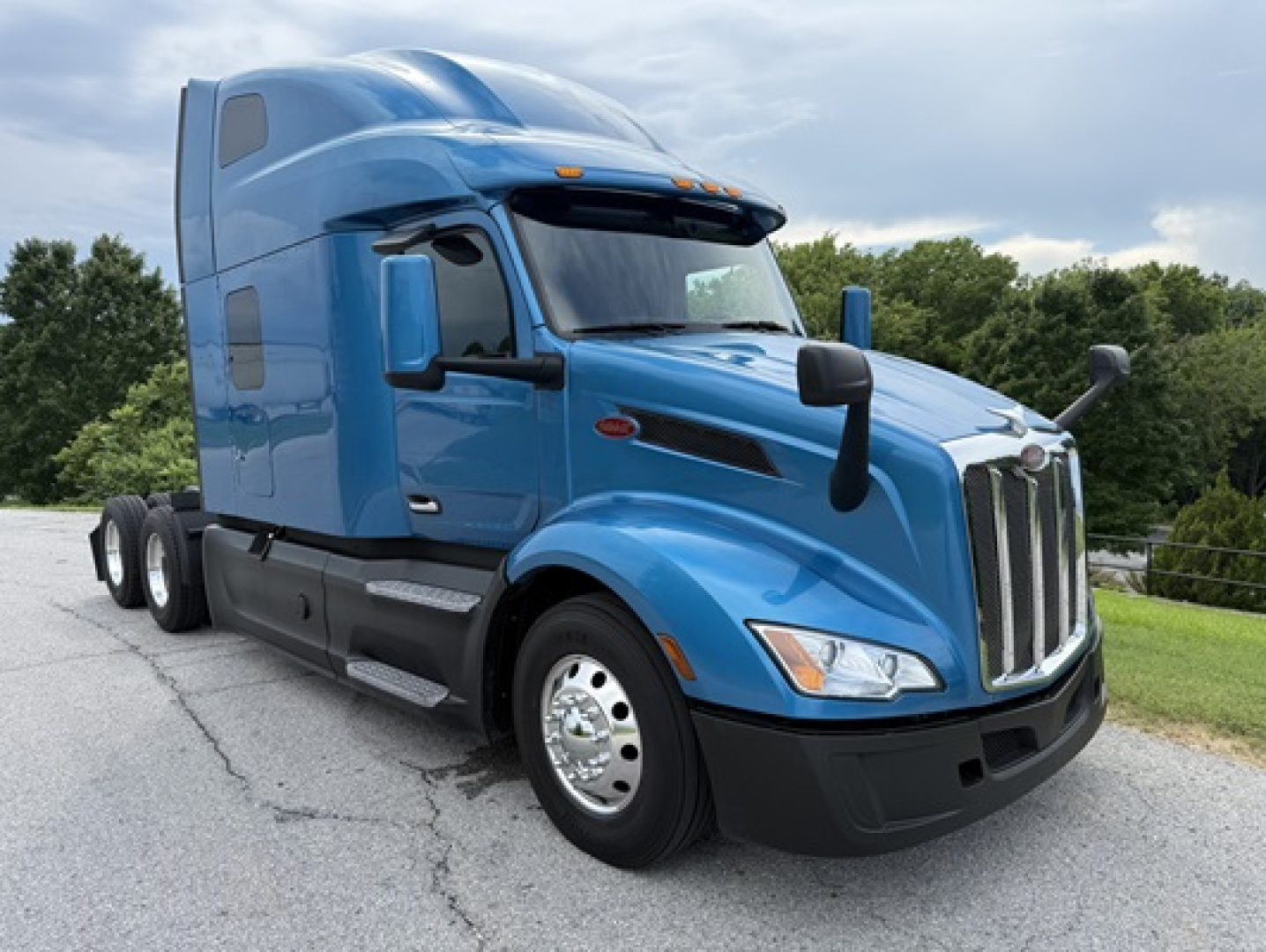 Peterbilt 579 conventional sleeper truck in blue, front-left view, highway tires and aerodynamic mirrors visible.