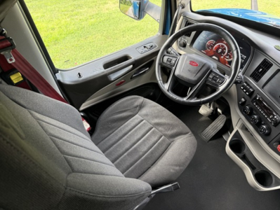 Truck cab interior showing steering wheel, dashboard, and driver seat of a Peterbilt 579; visible text on instrument cluster and controls.