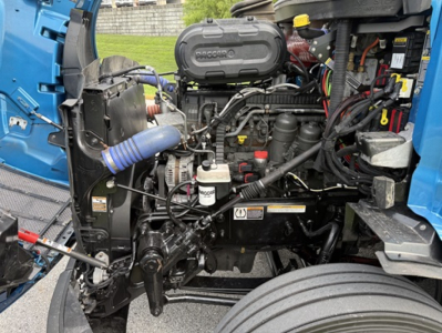 Peterbilt 579 engine bay showing diesel engine with hoses, coolant reservoir, and wiring harnesses.