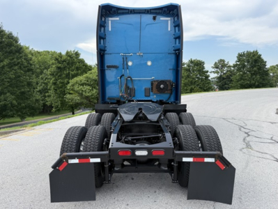 Peterbilt 579 truck chassis rear view showing blue cab interior, dual rear axles, mud flaps, and fifth wheel area.