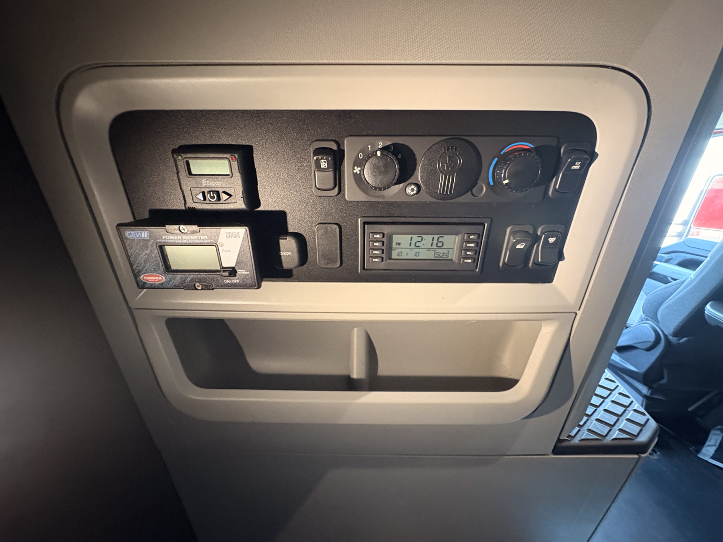 Kenworth T680 interior dash panel showing gauges and cab controls, digital clock, and small device mounted in overhead console.