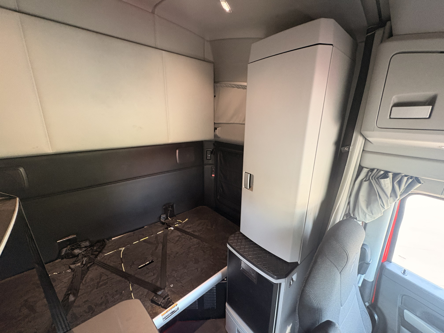 Kenworth T680 truck interior side sleeper area showing storage cabinet and seating mount.