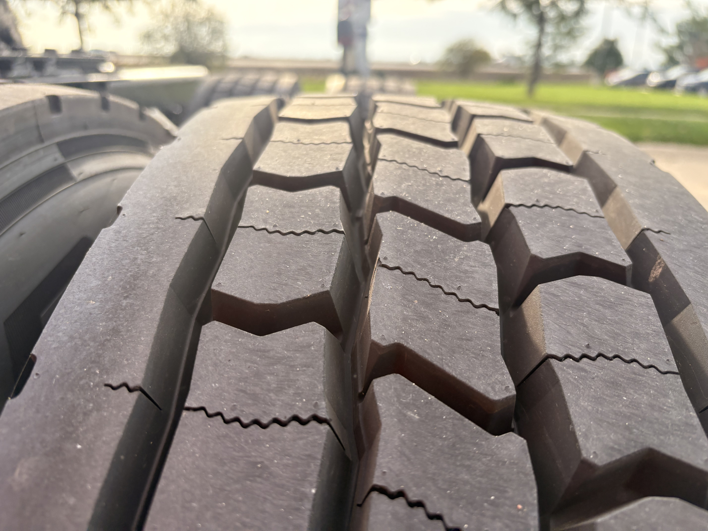 Tire treads on a Kenworth T680 truck shown in close-up, with vehicle information text in the background listing VIN 1XKYD49X7PJ230500, stock 0632231, conventional sleeper, used.
