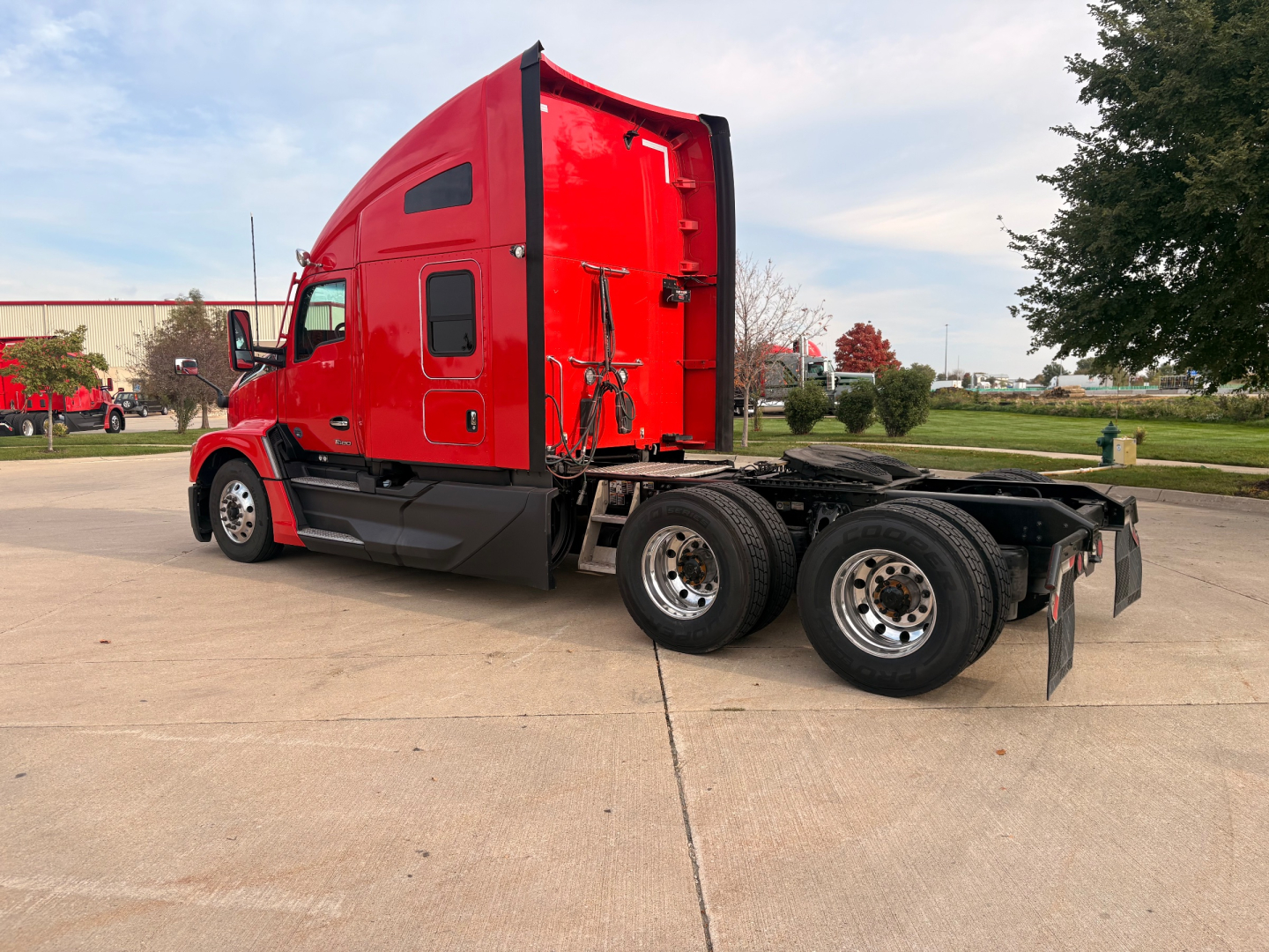 Kenworth T680 tractor cab and chassis side view showing red exterior, dual rear axles, and fifth wheel mounting.