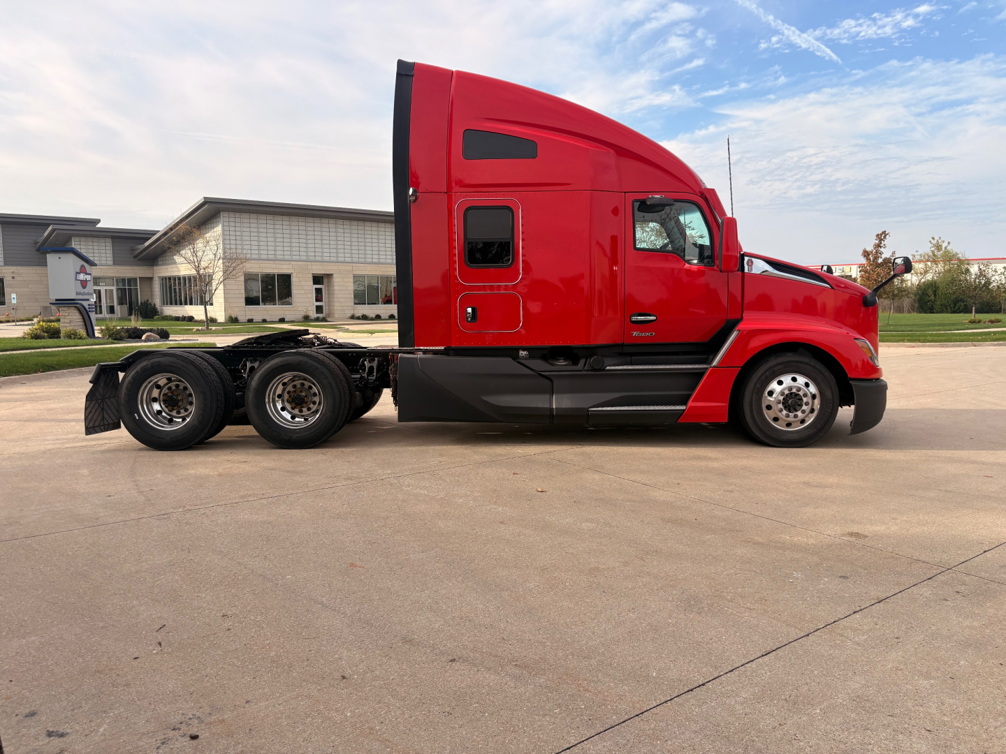 Kenworth T680 tractor in red with sleeper cab, side view showing tractor and wheel configuration.