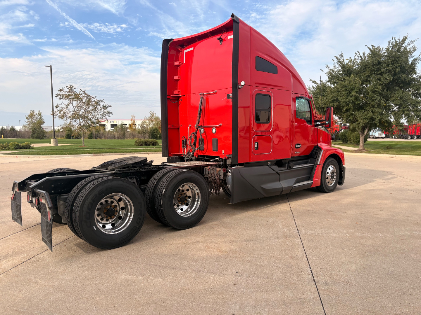 Kenworth T680 truck side rear view showing sleeper cab, red exterior, dual rear axles, unpaired fifth wheel area, and wheel assemblies.