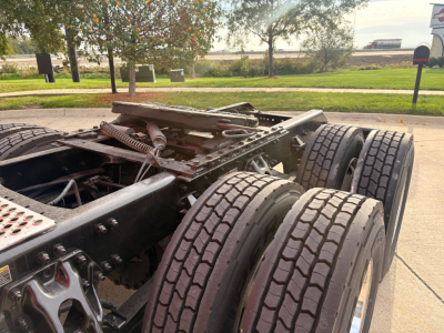 Kenworth truck chassis view showing multiple rear axles and tires. No labels readable on components. The image focuses on the undercarriage and wheel assembly without visible serials or fluid labels.
