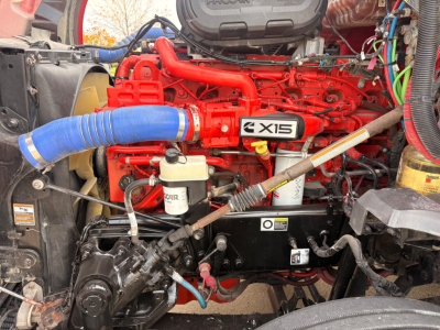 Kenworth T680 engine bay with bright red engine and blue intake hose; various components labeled, including Excel 6-cylinder engine block and fluid reservoirs visible.