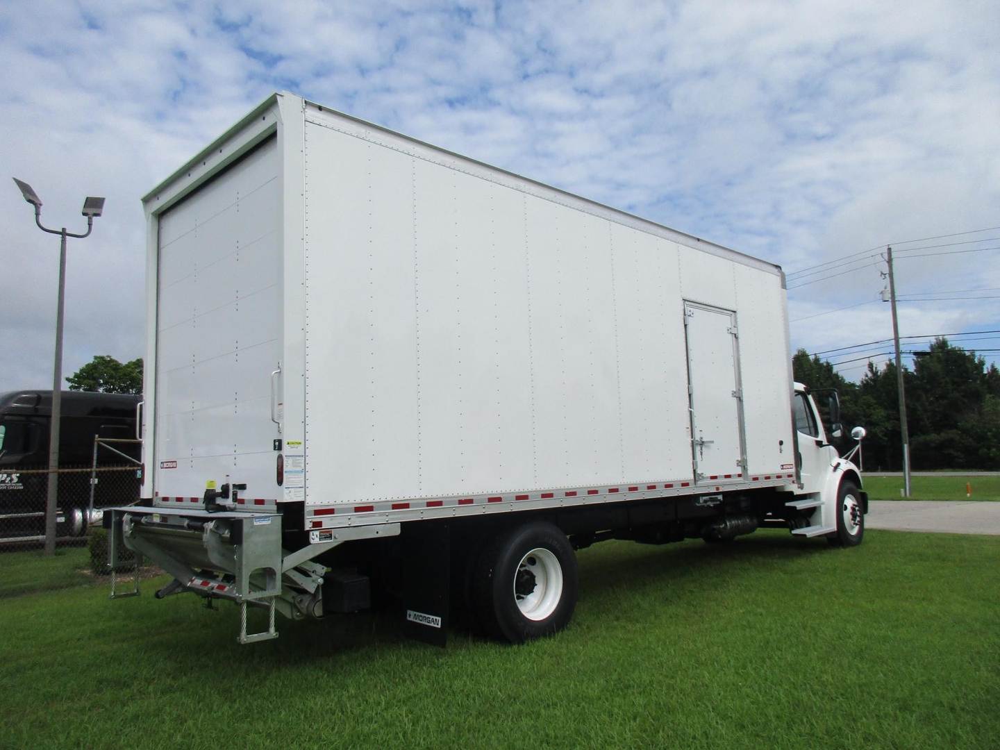 Freightliner M2 106 box truck side-and-rear view showing large white box body, dual rear wheels, and side entry door; no visible branding on box.