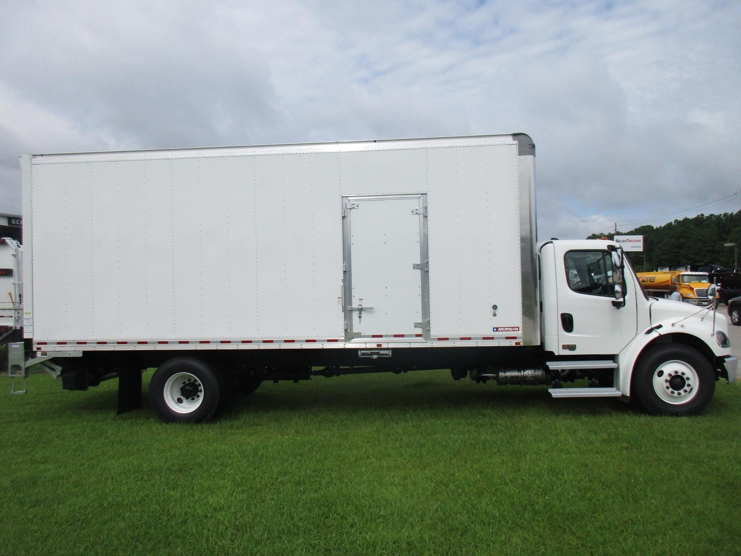 Freightliner M2 106 box truck side view showing cab and cargo box with side door and white paint
