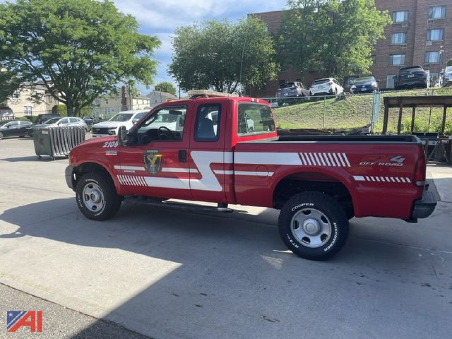 Ford F-350 Super Duty emergency response pickup with red cab and white decals, side stripes, and emergency insignia on door, parked outdoors.