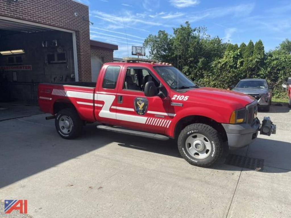 Red Ford F-350 XL Super Duty emergency response pickup with white diagonal stripes, emergency badge on door, '2105' decal on front fender, parked outside building.