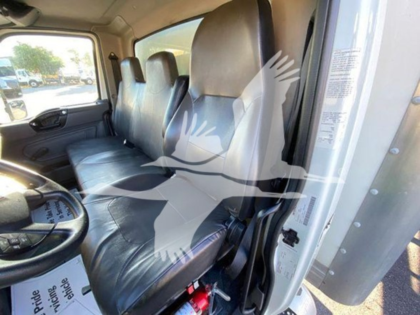 Truck cab interior showing front bench seats and steering wheel in a 2020 International MV with vinyl seating and light gray interior.
