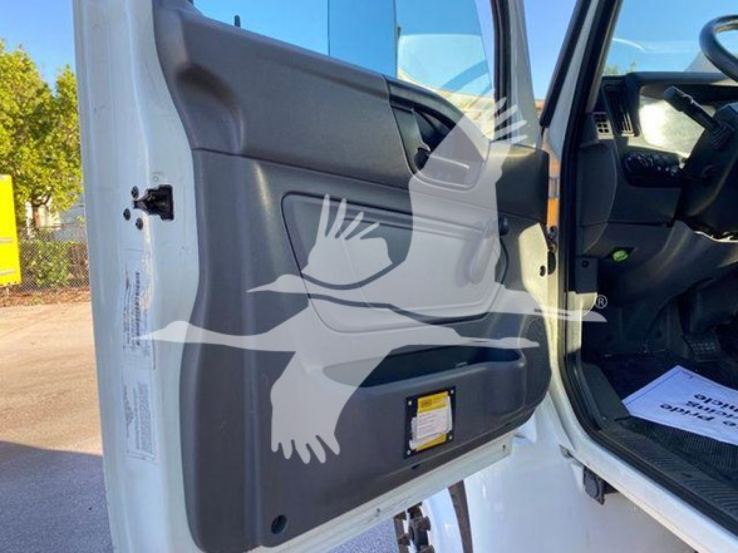 Truck cab interior door panel of a 2020 International MV, front driver door open, showing interior and partial dashboard.