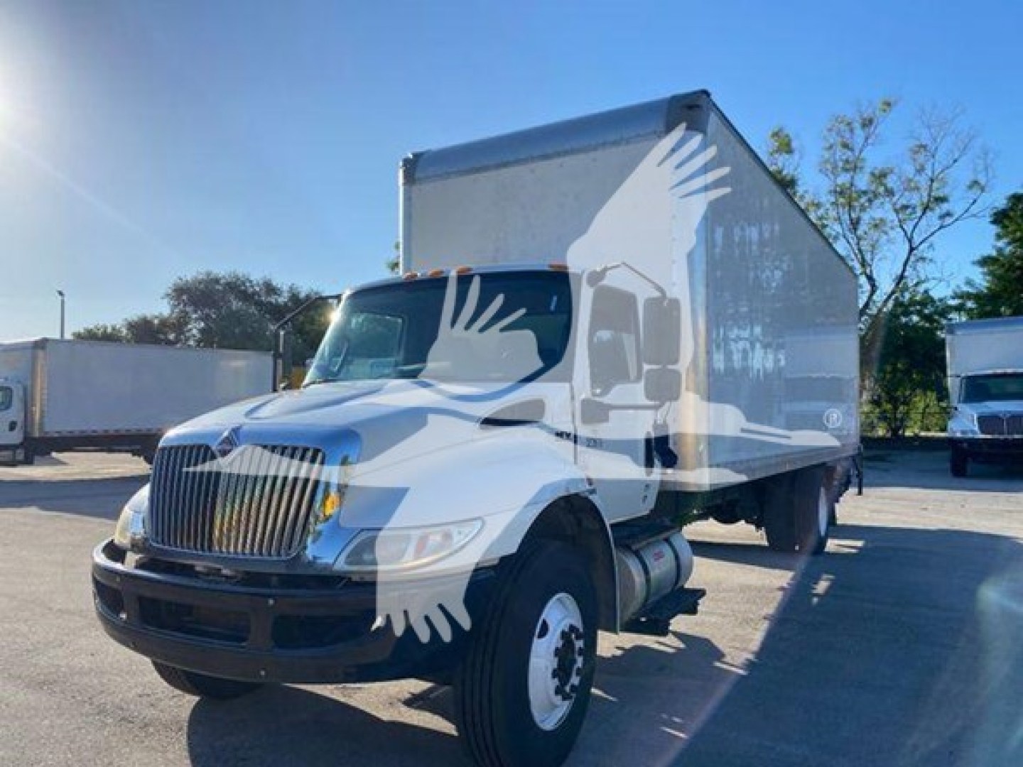 Box truck with white cab and box body, International heavy-duty truck, front grille, dual rear wheels visible, no visible text on side panels.