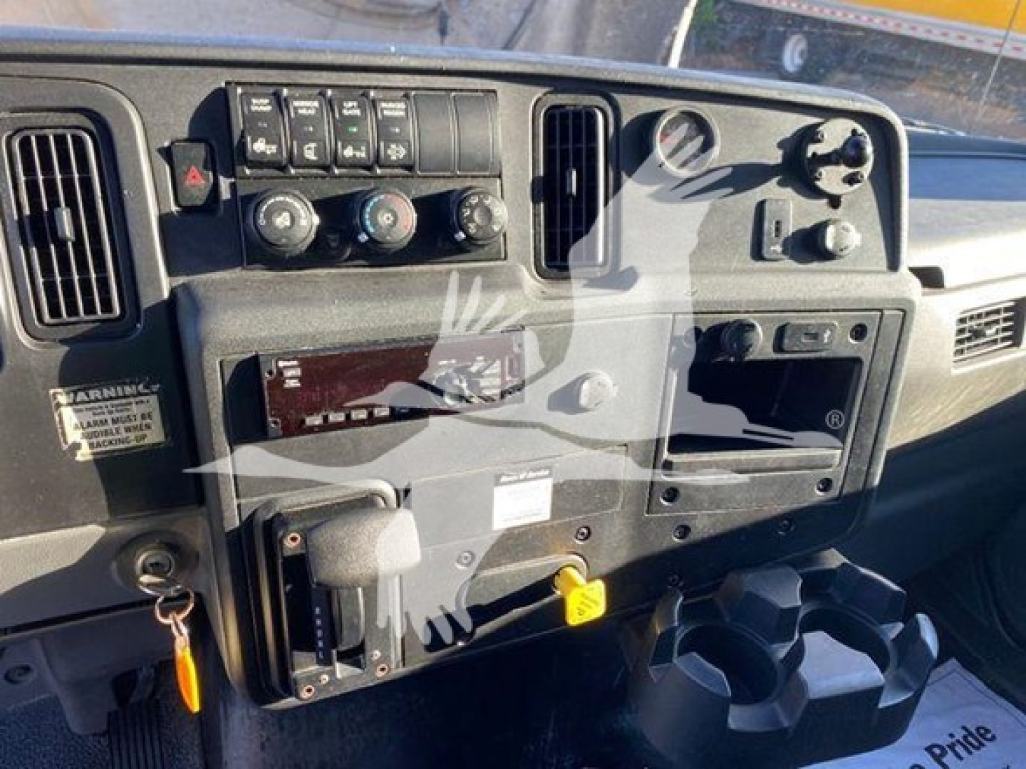 Dashboard view of a 2020 International MV truck showing instrument panel, climate controls, ignition area, vanity panels, and cup holder; VIN 3HAEUMML3LL207913 and stock tag visible.
