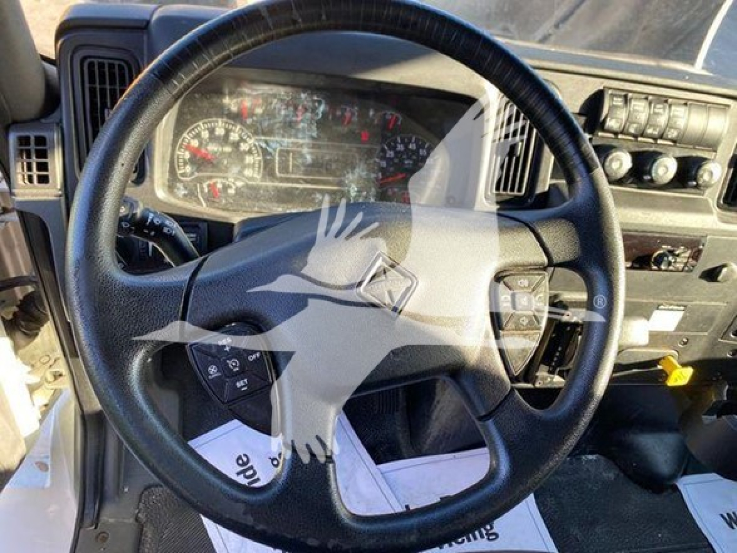 Truck interior focusing on steering wheel and dashboard of a 2020 International MV box truck showing instrument cluster, steering wheel controls, and center console.