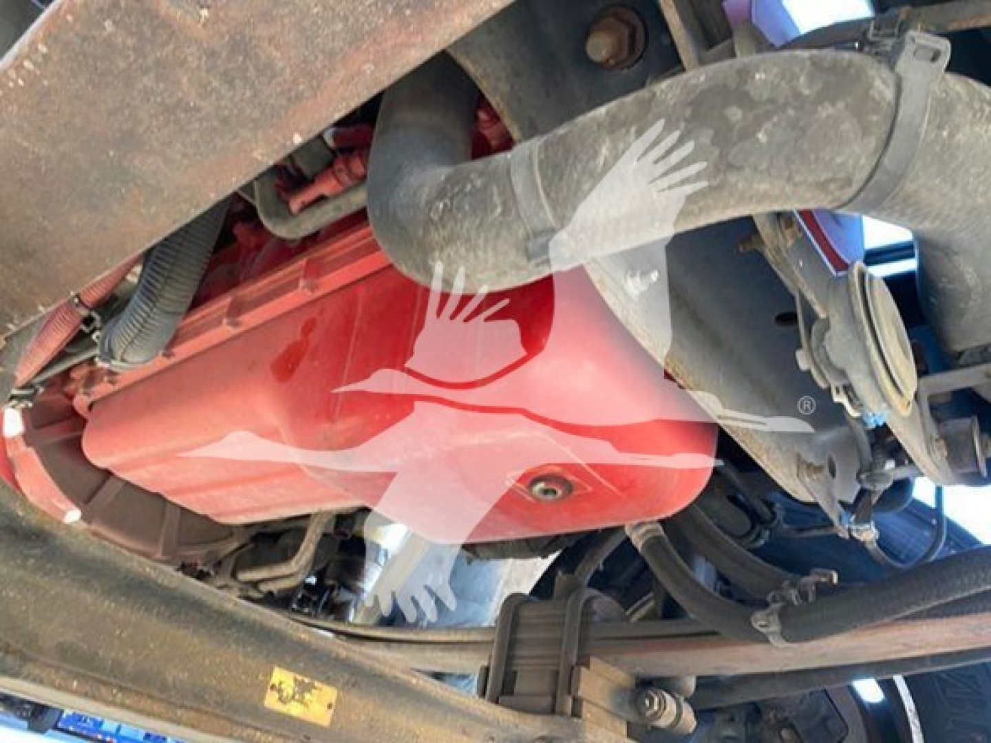 Truck engine bay view showing red engine cover with black hoses and surrounding chassis components.