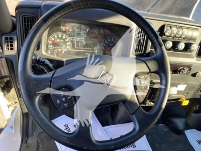 Truck interior focusing on steering wheel and dashboard of a 2020 International MV box truck showing instrument cluster, steering wheel controls, and center console.