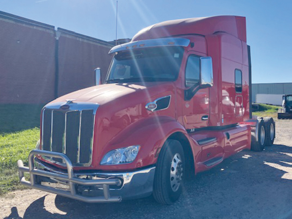 Peterbilt 579 UltraCab sleeper tractor in red, front and side view showing chrome bumper guard, grille, and dual rear axles.