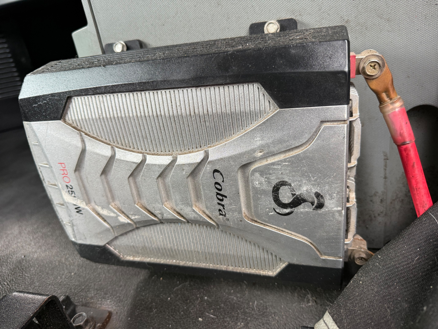 Cobra fuel or auxiliary device mounted in a Kenworth T680 engine bay with red battery cable and labeled components visible.
