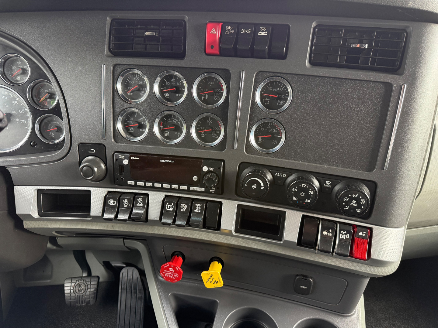 Kenworth T680 dashboard and center console showing multiple gauges, switches, and ignition area.