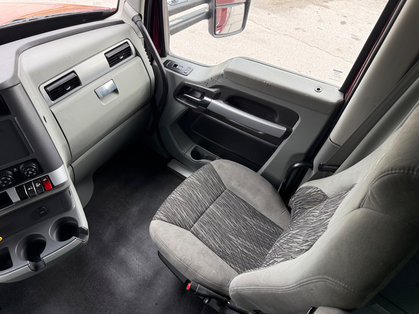 Interior of a Kenworth truck cab showing front passenger seat and dashboard area with steering wheel and door panel.