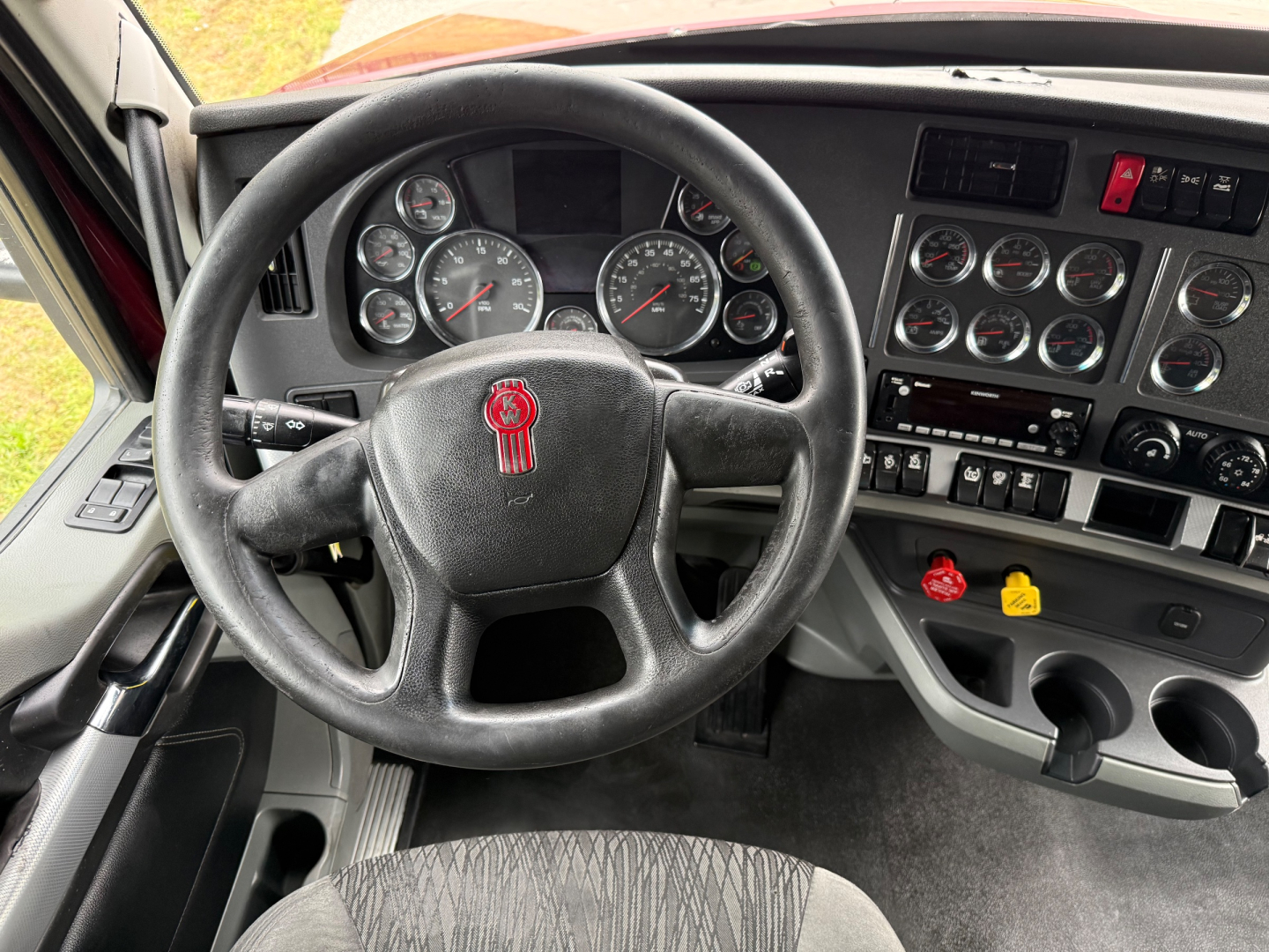 Kenworth T680 interior cockpit showing steering wheel and dashboard with gauges and controls.